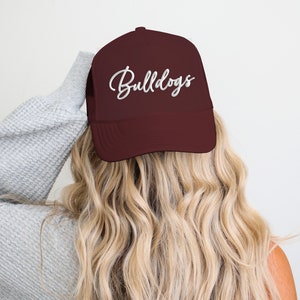 May include: A maroon trucker hat with a white embroidered script that says "Bulldogs".