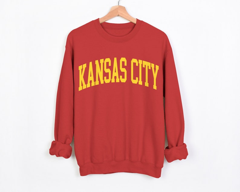 May include: Red sweatshirt with the text "KANSAS CITY" in yellow letters.