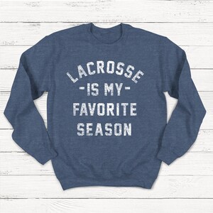 May include: A navy blue sweatshirt with the text "Lacrosse - Is My - Favorite Season" in white.