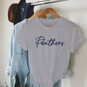May include: Gray t-shirt with a navy blue cursive inscription that reads "Panthers".