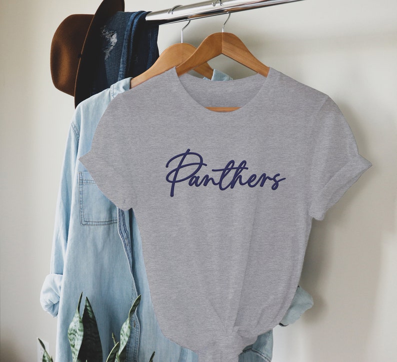 May include: Gray t-shirt with a navy blue cursive inscription that reads "Panthers".
