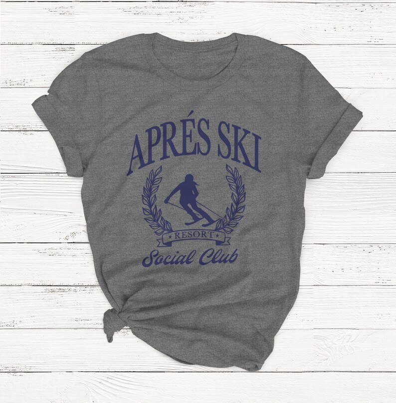 May include: Gray t-shirt with a blue graphic that says "Apr&egrave;s Ski Resort Social Club". The graphic features a skier in a wreath.