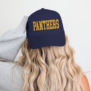 May include: A navy blue trucker hat with a gold embroidered "PANTHERS" logo.