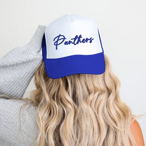 May include: A white and blue trucker hat with the word "Panthers" embroidered in blue on the front.