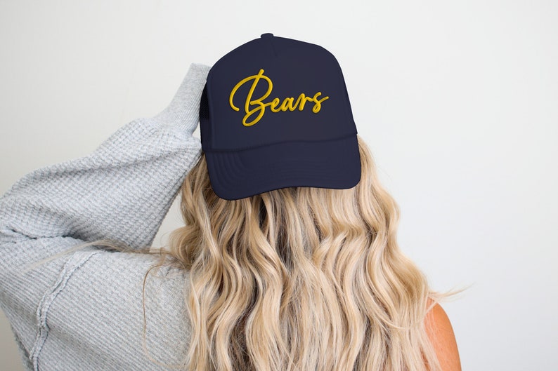 May include: A navy blue trucker hat with a gold embroidered cursive word "Bears" on the front.
