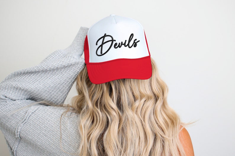May include: A white and red trucker hat with a black cursive script that says "Devils".