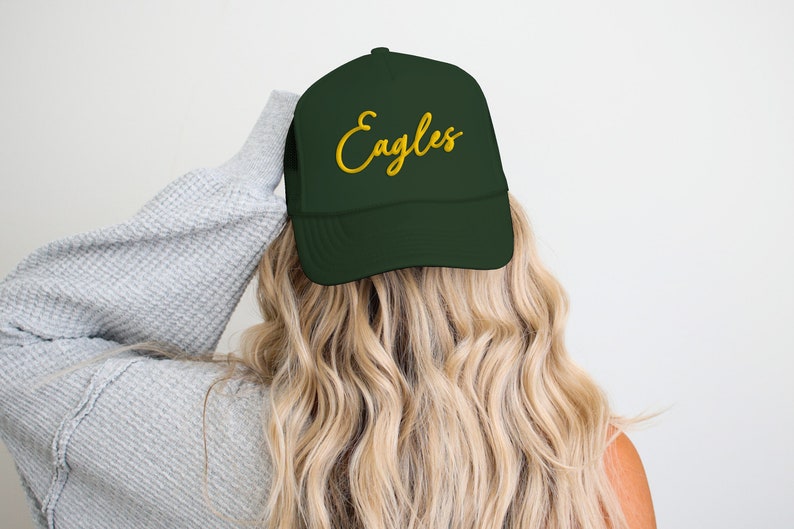 May include: A dark green trucker hat with a gold embroidered script that says "Eagles".