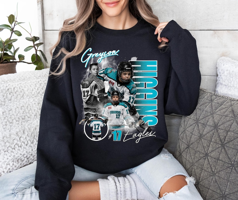 May include: Black sweatshirt featuring a collage of hockey player images. The design includes the name "Greyon Higgins" in a script font, with the name "HIGGINS" in large teal letters. The number "17" is prominent, along with the text "#17 Eagles".