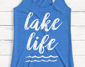 May include: A blue tank top with the text "lake life" in white lettering. The text is in a cursive font and has a wavy line underneath it.
