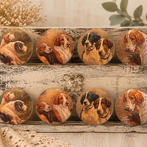 May include: Set of eight round coasters featuring vintage-style dog portraits. Each coaster showcases a different pair or individual dog, painted in warm brown, tan, and black tones. The coasters are displayed on a distressed white wooden box.