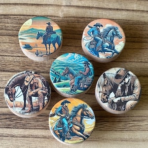 May include: Six round wooden coasters with colorful images of cowboys riding horses in various settings. The coasters feature a variety of landscapes, including a sunset, a mountain range, and a field of grass.