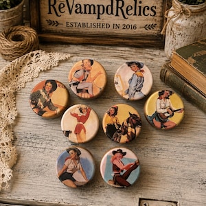 May include: A collection of seven circular wooden knobs, each featuring a distinct colorful illustration of a cowgirl in various poses. The designs include figures wearing hats, shirts, and vests, with some depicted alongside a horse or a guitar.