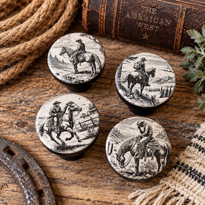 May include: Four round cabinet knobs featuring black and white illustrations of cowboys on horseback. Each knob displays a different scene, including a rider on a cliff, a person on a horse near trees, a galloping horse, and a rider resting on a horse.