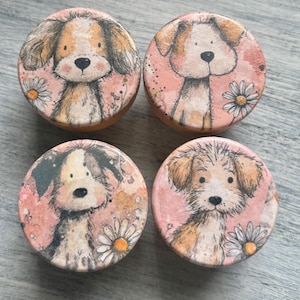 May include: Four round wooden decorative pieces with dog illustrations. Each piece features a different dog design with a pink background and white daisy accents. The dogs have brown, tan, and black fur.