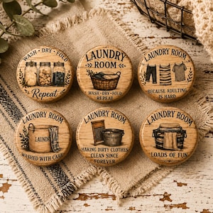May include: Six round wooden signs with laundry-themed designs. Each sign features the words "Laundry Room" and various phrases like "Wash, Dry, Fold, Repeat" and "Loads of Fun." The signs have a rustic, farmhouse aesthetic.