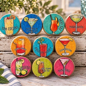May include: A set of nine round wooden coasters featuring colorful illustrations of cocktails including Tom Collins, Vodka Gimlet, Mai Tai, Margarita, Tequila Sunrise, Bloody Mary, Cosmopolitan, Mojito, Long Island Iced Tea, and Martini.