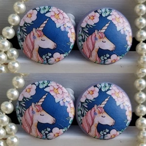 May include: Four round wooden knobs with a blue background and pink flowers. Each knob features a white unicorn with a pink mane and horn.
