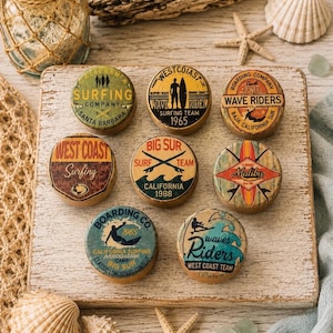 May include: Eight circular wooden coasters featuring vintage-style surfing graphics. Designs include text such as 'Surfing Company Santa Barbara', 'West Coast Wave Rider 1965', 'Wave Riders Baja California Sur', 'Big Sur Surf Team 1988', and 'Malibu'.