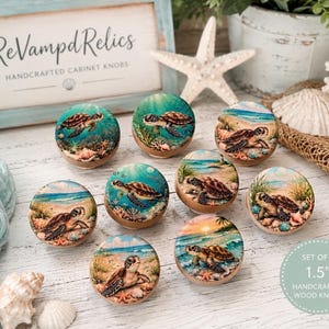 May include: A set of eight round wooden cabinet knobs, each 1.5 inches in diameter, featuring detailed illustrations of sea turtles in various coastal and underwater settings with sandy beaches, ocean waves, and coral reefs in shades of blue and tan.