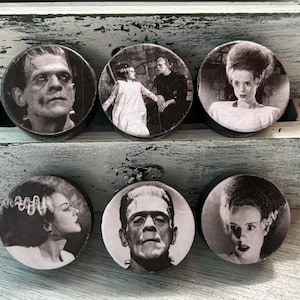 May include: Six round black and white coasters with images of classic horror movie characters. The coasters feature images of Frankenstein's monster, Dracula, the Creature from the Black Lagoon, and the Bride of Frankenstein.