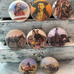 May include: Set of 8 round ceramic drawer knobs with vintage western themed images. The knobs feature cowboys, horses, and landscapes. The knobs are in various colors, including brown, white, and blue.