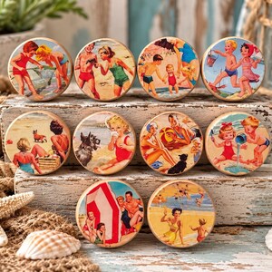 May include: A set of ten round wooden knobs featuring vintage-style illustrations of people at the beach. Each knob displays a unique scene with children and adults in swimwear, playing in the sand, swimming, or relaxing near the ocean water.