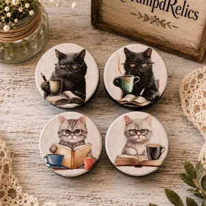 May include: Four circular wooden coasters featuring illustrations of cats wearing glasses. Two coasters show black cats reading books with coffee mugs, while the other two show grey tabby cats reading books with coffee mugs. Each coaster has a unique scene.