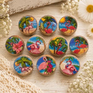 May include: A set of ten round wooden cabinet knobs, each featuring a unique hand-painted tropical scene with pink flamingos, palm trees, blue ocean water, and bright yellow suns. The knobs have a natural wood edge and a glossy, smooth finish.