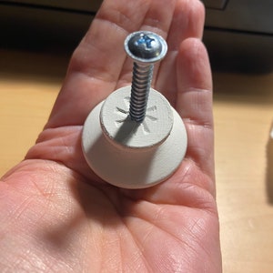 May include: White ceramic knob with a silver screw. The knob has a star-shaped design on the top.