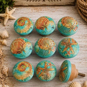 May include: A set of nine round cabinet knobs featuring a turquoise blue background with printed orange and tan seashell and starfish designs. Each knob has a smooth, rounded surface and a wooden base with a metal screw for installation.