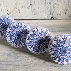 May include: Four blue and white ceramic knobs with a floral pattern. The knobs are round and have a raised design.