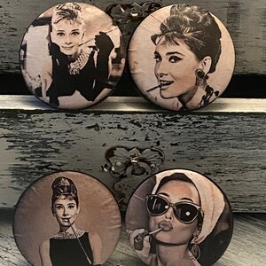 May include: Four round, decorative, wooden knobs with images of Audrey Hepburn. Each knob features a different image of Hepburn in black and white. The knobs are perfect for adding a touch of vintage glamour to any home.