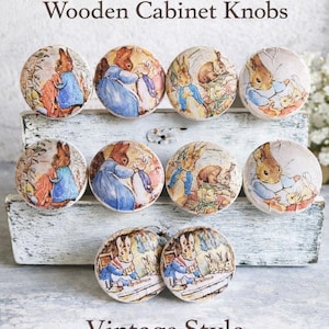 May include: Set of 10 wooden cabinet knobs featuring illustrations of Peter Rabbit and other characters from Beatrix Potter stories. The knobs are round with a vintage style and are designed as children's storybook drawer pulls.