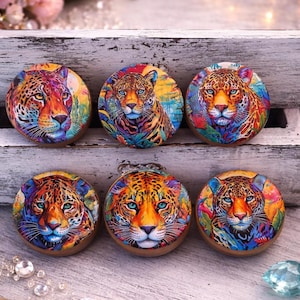May include: Six round decorative coasters featuring vibrant, colorful jaguar portraits. Each coaster showcases a unique jaguar design with vivid hues of orange, blue, and purple. The coasters have a wooden border.