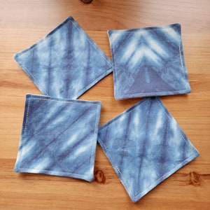 May include: Four blue and white tie-dye fabric coasters with gold stitching.