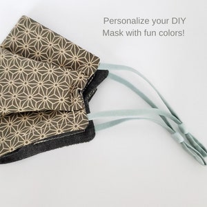 May include: A face mask with a geometric pattern in beige and brown colors. The mask has light blue elastic straps. The text "Personalize your DIY Mask with fun colors!" is visible in the image.
