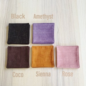 May include: Five square fabric coasters in different colors: black, amethyst, coco, sienna, and rose.
