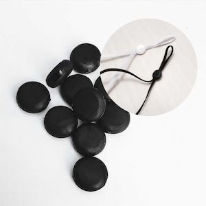May include: A set of ten black silicone stoppers for mask ear loops. The stoppers are round and have a small hole in the center.