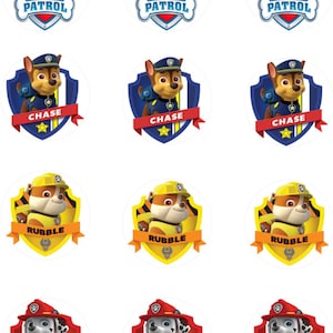 May include: Twelve round cupcake toppers featuring characters from the cartoon show Paw Patrol. The toppers feature the Paw Patrol logo, Chase, Rubble, and Marshall.