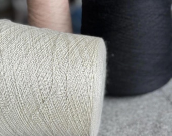May include: Three spools of yarn, one is light pink, one is black, and one is a light gray color.