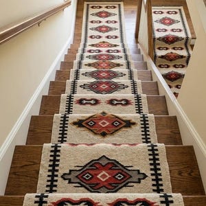 Può includere: Una lunga passatoia per scale con base color crema e motivi geometrici a rombi ripetuti in rosso, nero e grigio. La passatoia presenta un bordo nero spesso lungo i lati ed è installata su una scala in legno.