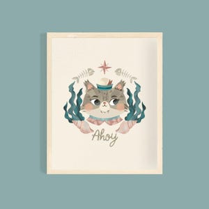 Puede incluir: Ilustración enmarcada de un gato con gorro de marinero, rodeado de elementos náuticos. El gato tiene pelaje gris y lleva un gorro azul y blanco. La palabra "Ahoy" está escrita en cursiva debajo.