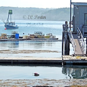 May include: A wooden dock with a ramp leading up to a gray building on stilts. The building has a window and a door. There is a small boat in the water in the background. The text "© EC Porter PhotoArt" is visible in the image.