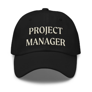 May include: A black baseball cap with the text "PROJECT MANAGER" embroidered in white on the front.