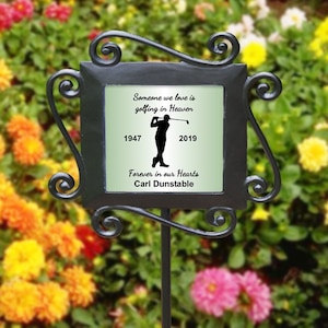 May include: Black metal garden stake with a green and white ceramic plaque. The plaque has a silhouette of a golfer and the text "Someone we love is golfing in Heaven 1947 2019 Forever in our Hearts Carl Dunstable".