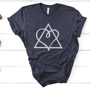 May include: Navy blue t-shirt featuring a white geometric design of a heart within a triangle. The shirt is made of a soft material and has rolled-up sleeves. The design is centered on the front of the shirt.
