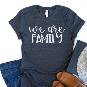 May include: A dark gray t-shirt with the text "we are family" in white lettering.