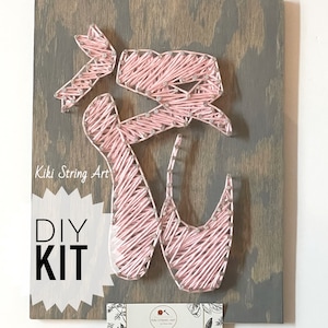 May include: DIY string art kit featuring a pink ballet shoe design on a wooden board. The kit includes all the materials needed to create the art, including string, nails, and a wooden board. The kit is perfect for beginners and experienced crafters alike.