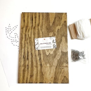 May include: A string art kit with a wooden board, white string, and a bag of nails. The design is a simple leaf pattern.