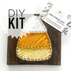 May include: DIY string art kit featuring a candy corn design. The kit includes a wooden base, yarn in yellow, white, and orange, and nails.